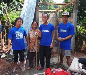 Herr Tong je Va steht mit einer Frau und 2 Bauerabeitern vor seiner im Rohbau befindlichen Toilette. Die Männer tragen ein blaue T-Shirt.