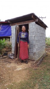 Gestützt auf eine Gehhilfe steht Frau Me Tau Ta vor einer gut aufgebauten Toilette. 