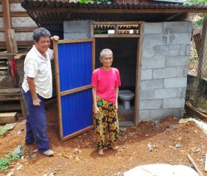 Frau Tau Lah aus Ban Nam Sai thouang steht mit dem Baumeister neben ihrer neuen Toilette
