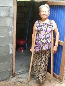 Frau Gong steht gestützt auf Gehhilfen vor ihrer neuen Toilette